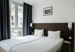 パリにあるHôtel Beaurepaireの大きな窓が備わるホテルルームのベッド1台分です。