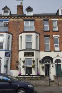 a brick building with a tree tombs public house at Pretoria Guest House in Bridlington