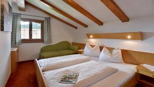 a bedroom with a bed and a green chair at Appartements am Römerweg in Oberndorf in Tirol +72 photos