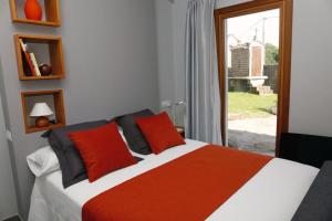 sypialnia z łóżkiem z czerwonymi poduszkami i oknem w obiekcie Galpon Boutique Aldea De Abaixo w mieście Palas de Rei 