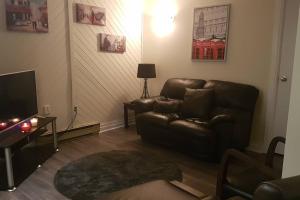a living room with a leather couch and a television at 2-Bedroom Apartment Sweet #5 by Amazing Property Rentals in Gatineau