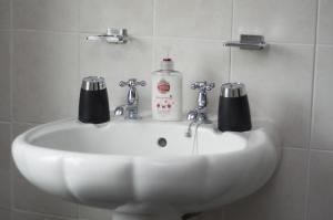 a bathroom sink with a bottle of soap on it at Pretoria Guest House in Bridlington