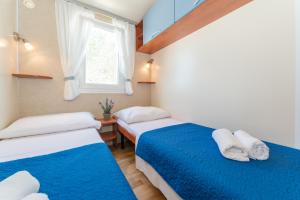 Duas camas num pequeno quarto com uma janela em Mobile home Laguna em Sveti Petar