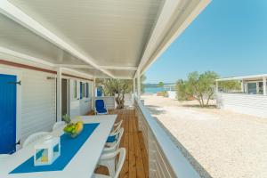 un porche con una mesa y sillas azules y la playa en Mobile home Laguna en Sveti Petar