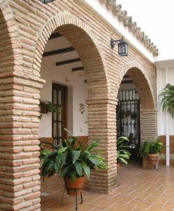 une arche en briques avec deux plantes en pot sur une terrasse dans l'établissement El Perro de Paterna, à Paterna de Rivera