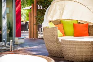 a wicker chair with colorful pillows on a patio at Das Frühstückshotel Sankt Peter-Ording in Sankt Peter-Ording