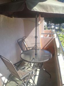 a table and chairs on a balcony with an umbrella at Guesthouse Lautasevic in Petrovac na Moru