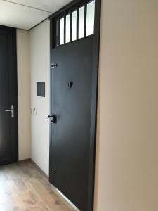 een zwarte deur in een kamer met een raam bij Voormalig Politiebureau in Overloon