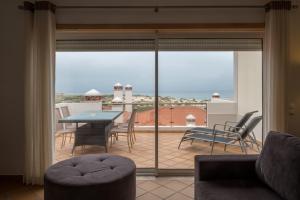 een woonkamer met uitzicht op een patio met een tafel en stoelen bij Maravilhoso T2 Vila da Praia in Amoreira