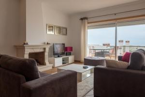 een woonkamer met banken, een tv en een open haard bij Maravilhoso T2 Vila da Praia in Amoreira