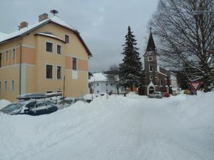 una strada ricoperta di neve accanto a una chiesa di Apartman na Kvilde - Sumava a Kvilda