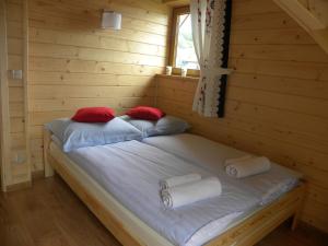 MizernaにあるFamiliówkaの赤い枕2つが備わるログキャビンのベッド1台分です。