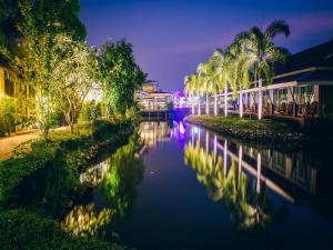 un río con palmeras y edificios por la noche en Good Times Resort -SHA Extra Plus, en Kanchanaburi