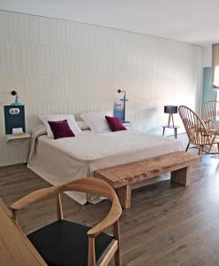 a bedroom with a large bed and a wooden bench at Hotel Ayllon in Ayllón