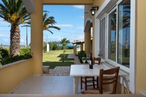 a porch with a white table and chairs and a palm tree at Residence Vista Del Mare in Acharavi