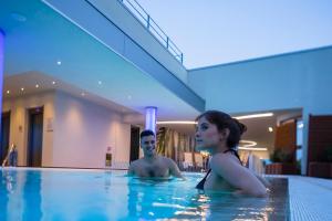 a man and a woman in a swimming pool at Hotel Ambassador in Bibione