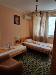 two beds in a room with a chair and a window at Guest Rooms Denitsa in Obzor