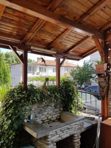 a wooden pergola with a chicken sitting on a stone wall at Guest Rooms Denitsa in Obzor