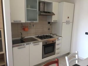 una cucina con armadi bianchi, lavandino e piano cottura di Luca's a Sesto Fiorentino
