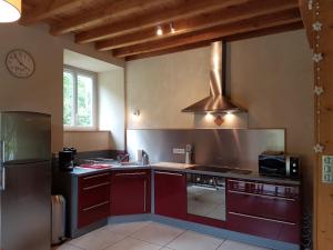 a kitchen with red cabinets and a stove top oven at Gite la Fargue de Cabre in Vicdessos