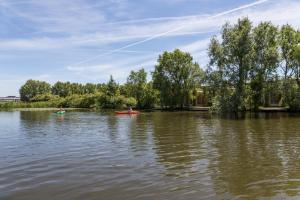 dos personas en kayaks en un río con árboles en De Groote Wijzend, en Lutjebroek