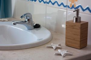 a bathroom with a sink and starfish on a counter at By the C house in Vila Nova de Milfontes