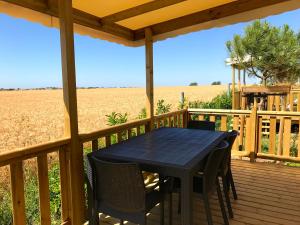 a table and chairs on a deck with a view of a field at Camping Paradis 4 étoiles Au Port de L'Houmeau - La Rochelle in LʼHoumeau