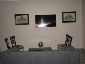 a room with a table and chairs and a flat screen tv at 4 Seam Guest House in Delmas