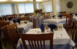 a dining room with tables and chairs with white tablecloths at Pensione Villa Joli in Lido di Jesolo