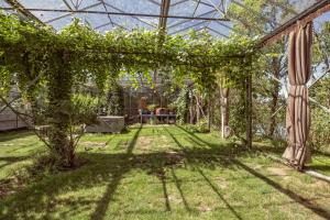 un jardín con una pérgola con vides. en De Groote Wijzend, en Lutjebroek