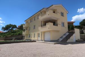 a large yellow building with a garage at Apartmani Marin in Vrbnik