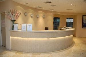 a lobby with a counter with clocks on the wall at Adi Hotel in Eilat