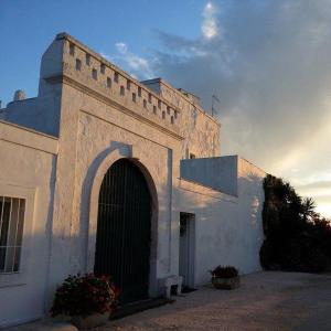 a white building with an archway in front of it at Masseria Boezio Ostuni Mare in Torre Santa Sabina