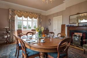 uma sala de jantar com uma mesa com cadeiras e uma lareira em Garrane House em Croom