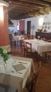a restaurant with white tables and chairs and plates on the wall at Il Salice Ridente in Pasiano di Pordenone