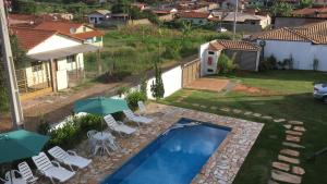 a backyard with a swimming pool with chairs and umbrellas at Pousada Vivendas Da Serra in Catas Altas