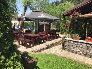 une terrasse avec des tables, des bancs et un parasol dans l'établissement Pensiunea Trei Ponei, à Corbeni