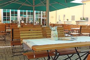 einen Tisch mit einem grünen Sonnenschirm in einem Restaurant in der Unterkunft Hotel & Brauereigasthof Drei Kronen in Memmelsdorf