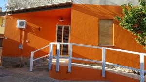 an orange building with a staircase on the side of it at B&B Le Peonie in Badesi