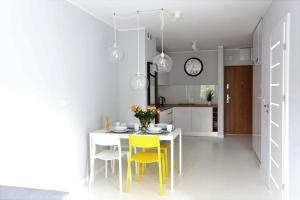 a kitchen with a white table and yellow chairs at Apartamentowiec Dwie Sosny in Ustronie Morskie