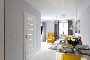 uma sala de estar com uma mesa e cadeiras amarelas em Apartamentowiec Dwie Sosny em Ustronie Morskie