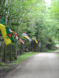 a group of flags flying over a dirt road at Adventures East Cottages and Campground in Baddeck Inlet