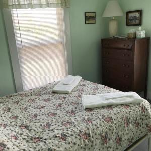 2 toallas en una cama en un dormitorio con ventana en The 8th Maine Regiment Lodge and Museum en Peaks Island