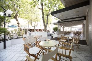 un patio esterno con tavoli, sedie e alberi di Hotel Impero a Rimini