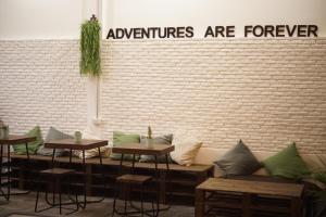 a row of tables and benches in front of a brick wall at Krit Hostel in Bangkok