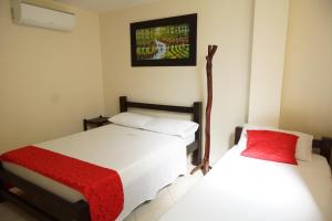 a bedroom with two beds and a picture on the wall at Hotel Esmeralda in San Gil