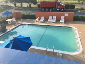 une grande piscine avec des chaises et un camion dans l'établissement Relax Inn Forth Worth, à Fort Worth