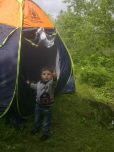 a young boy standing in front of a tent at Hotel Noy in Goris
