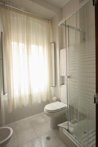 a bathroom with a toilet and a glass shower at Hotel Leiriense in Leiria