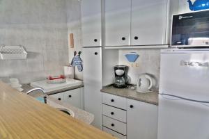 cocina con armarios blancos y nevera blanca en Torresol 208, en Nerja